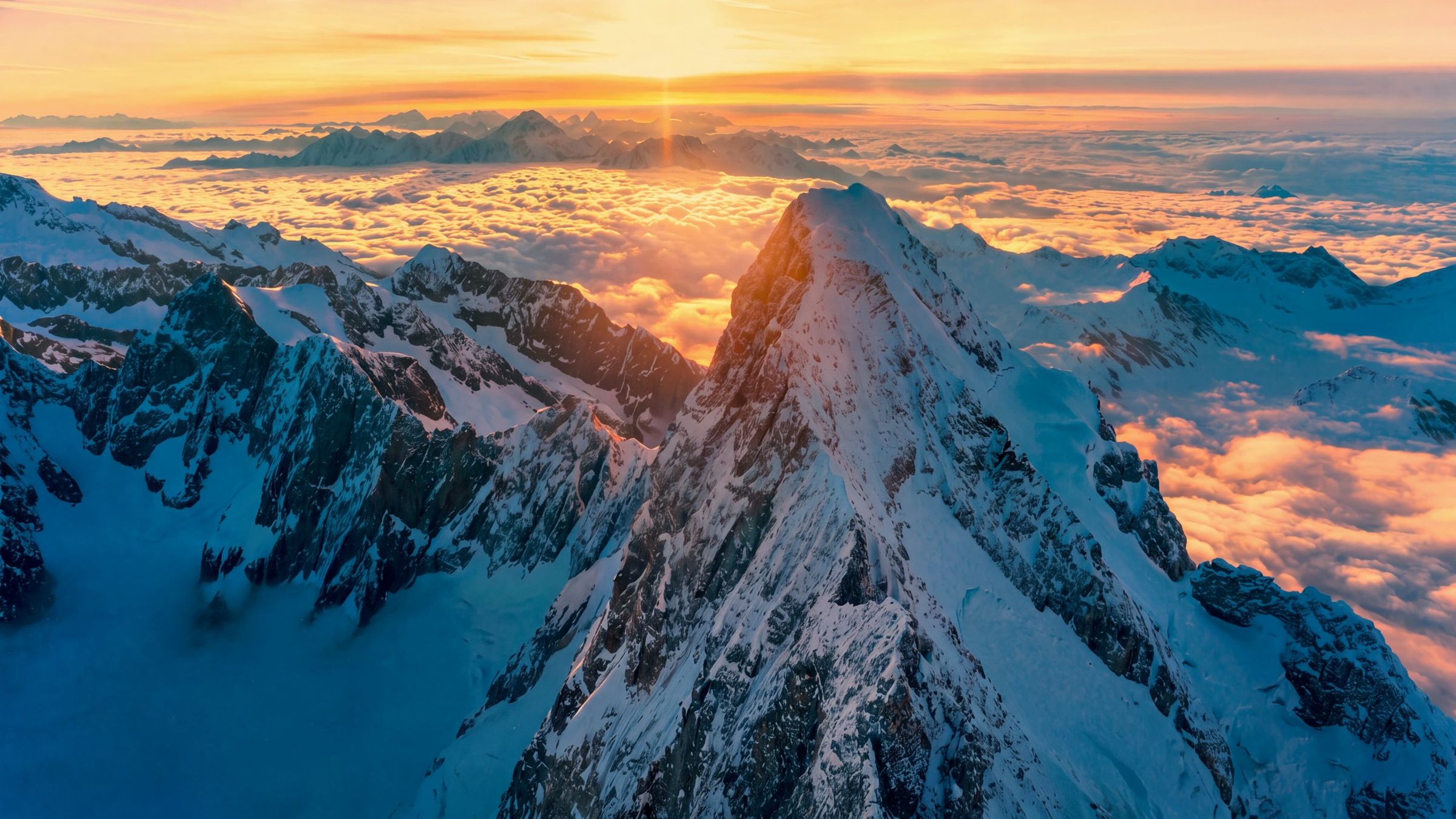 Aerial view of a snow peak above a sunlit sea of cloud