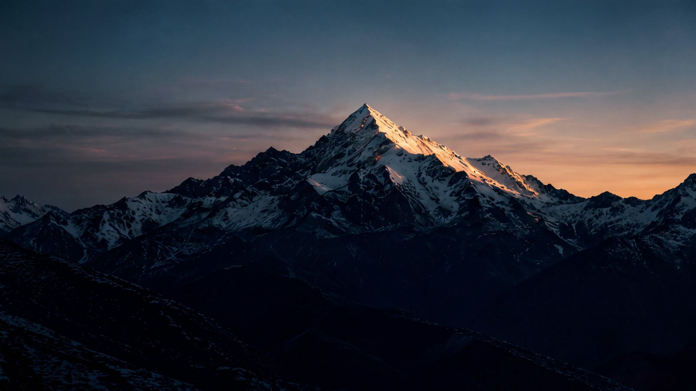 A snow-capped peak catching the last light at dusk